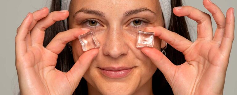 Mujer aplicando hielo en la cara con un cubo de hielo en cada mejilla, técnica de skincare para mejorar la piel