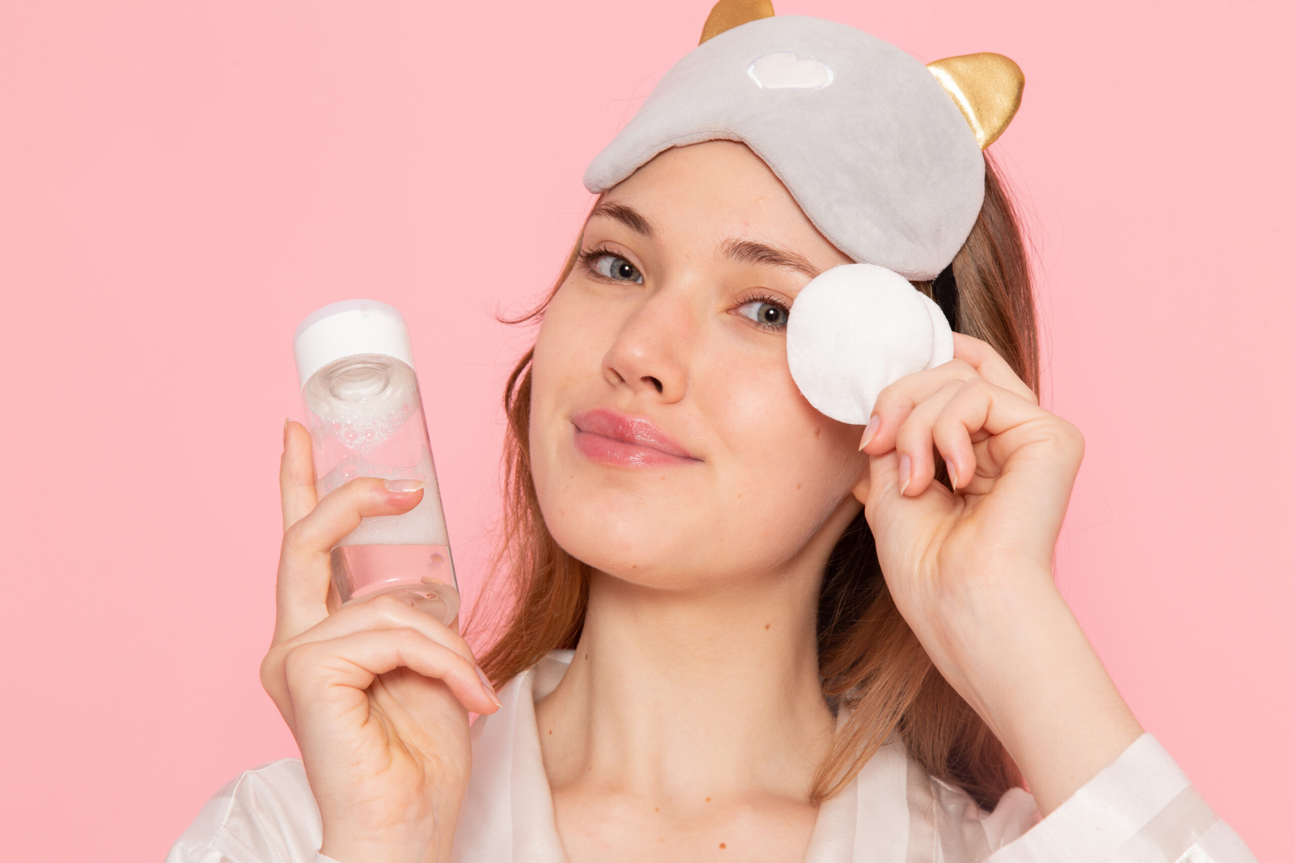 Mujer aplicando un desmaquillante bifásico con un pad de algodón para retirar el maquillaje de ojos.
