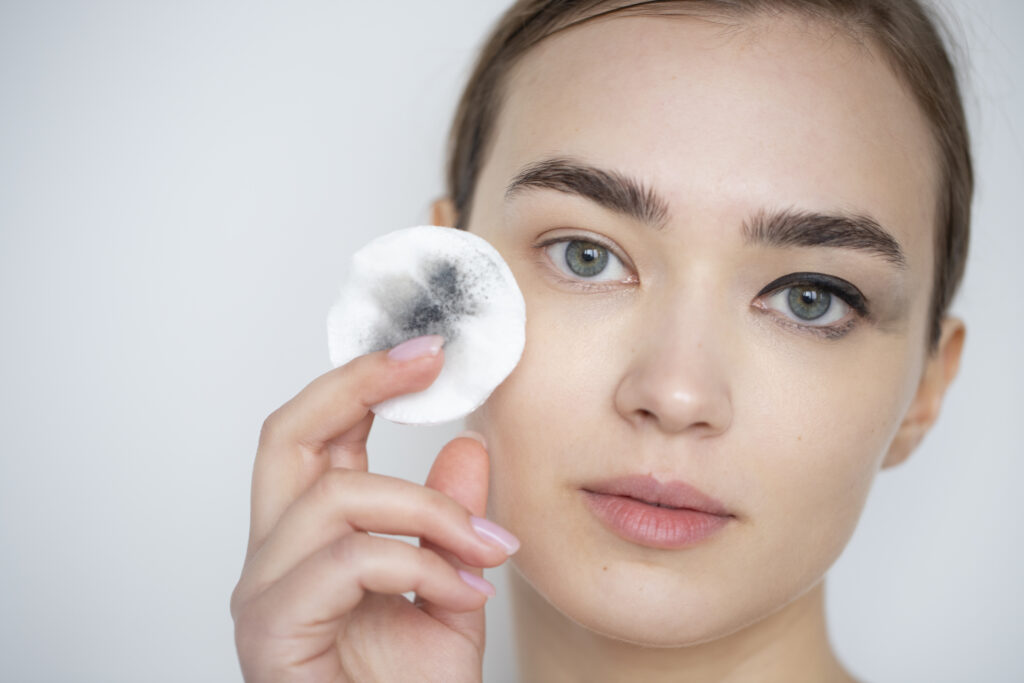 Mujer desmaquillando sus ojos con un pad facial de algodón empapado en desmaquillante